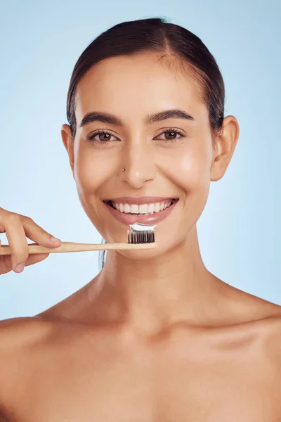 Brushing teeth, portrait and woman with dental, hygiene and grooming with oral care isolated on blue background. Female model cleaning mouth, health and morning routine and toothbrush with toothpaste.