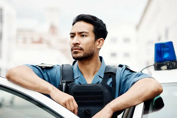 Police, thinking and man officer by a car for an investigation or patrol for law protection in city or urban town. Criminal, safety and legal service guard or security on duty for justice enforcement.