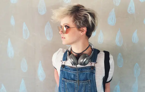 Fashion, music and a gen z woman thinking in studio on a rain wallpaper background for trendy style. Cyberpunk, idea and headphones with an attractive young female person looking cool or edgy.