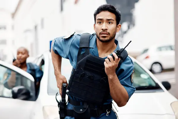 Asian man, police and walkie talkie with gun in city for suspect, communication or reinforcements. Serious male person, security guard or cop radio calling backup for crime in street of an urban town.