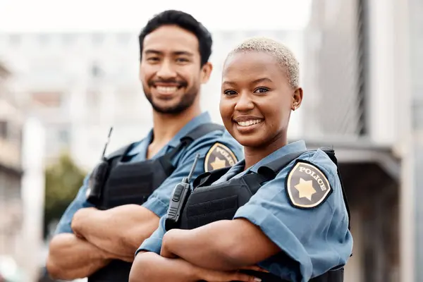 Happy police, team and arms crossed in confidence for city protection, law enforcement or crime. Portrait of man and woman officer standing ready for justice, security or teamwork in an urban town.