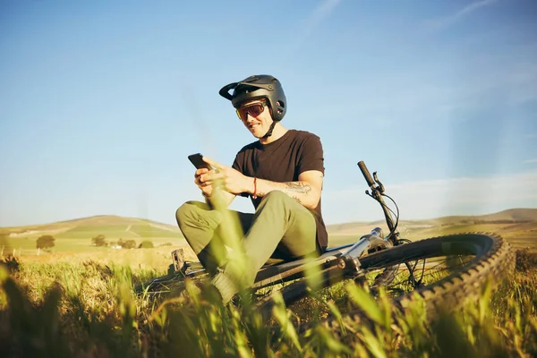 Phone, mountain bike and man outdoor in nature for extreme sports, training or workout. Smartphone, online communication and male person with bicycle for off road cycling, travel or adventure.