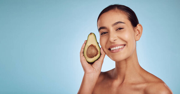 Woman, avocado and portrait, natural beauty and skincare with eco friendly product isolated on blue background. Mockup space, happy female model and banner, fruit and sustainability in dermatology.