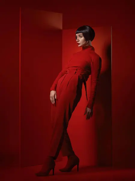 stock image Fashion, posing and a woman on a red background, thinking with a vision for style and aesthetic. Serious, idea and a retro model or girl in stylish clothes or a suit isolated on a studio backdrop.