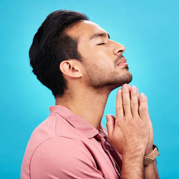 Profile, religion and praying man in studio isolated on a blue background. Christian, spiritual and male person with prayer, gratitude and faith to worship God, Jesus and Holy Spirit with meditation