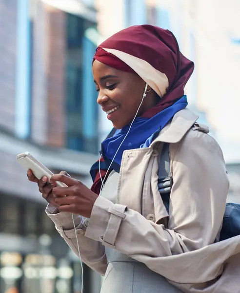 Phone, black woman travel or music in city on headphones for social media, motivation or mindset. Happy student girl on smartphone radio, listening or streaming audio podcast outdoor on urban street.