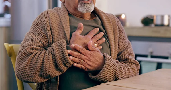 Hands, breathing and heart attack with a senior person in the dining room of a retirement home closeup. Healthcare, medical or emergency and an elderly adult with chest pain for cardiac arrest.