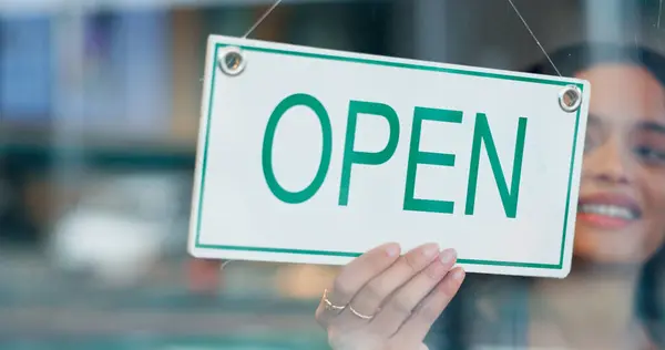 Happy woman, small business or open sign on window in coffee shop or restaurant ready for service. Advertising, start or entrepreneur holding board, poster or welcome for message in diner or cafe.