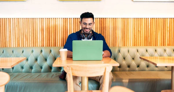 Happy man in cafe, typing on laptop and remote work, reading email or writing blog, article or search on tech. Computer, freelancer and editor in coffee shop, store or restaurant for project at table.