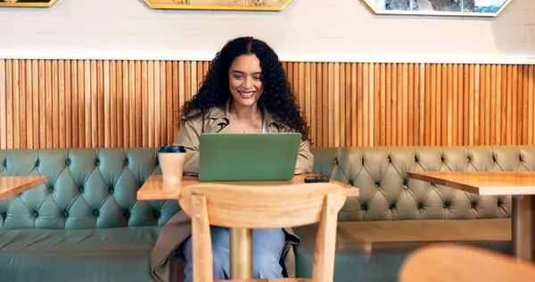 Happy woman in coffee shop, typing on laptop and remote work, reading email or writing blog, article or search on technology. Computer, freelancer or copywriting in cafe, store or restaurant at table.