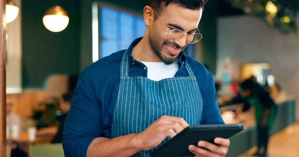 Cafe, man and business owner on tablet for restaurant sales, online management or customer service reviews. Happy entrepreneur, waiter or barista typing on digital technology for coffee shop startup.