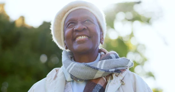 Face, thinking and smile with a senior black woman outdoor in a garden during summer for freedom. Nature, environment and happy with a nostalgic elderly person in a park for retirement wellness.
