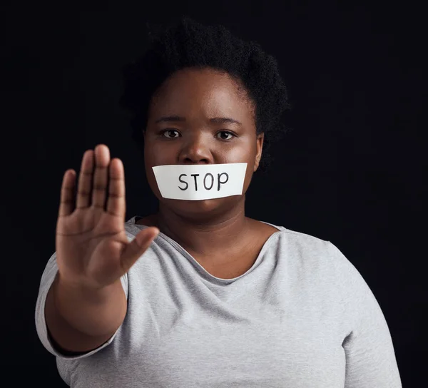 Portrait, stop and palm with a black woman in studio on a black background for gender equality or domestic violence. Hand, silence or abuse and a scared female victim with her mouth covered in fear.