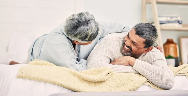 Lying, funny or old couple in bedroom to relax, enjoy romance or morning time together at home. Hugging, silly senior woman or happy elderly man laughing or bonding with love or smile in retirement.