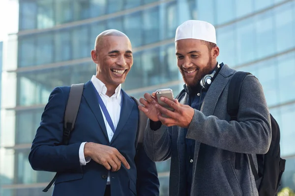 Phone, city and diversity business men for global networking, social media update and corporate collaboration. Happy black man with Arab, muslim or islamic partner on smartphone of international chat.