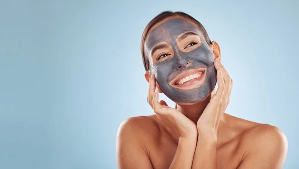 Woman, face mask and thinking of charcoal skincare, natural beauty and cosmetics benefits on studio, blue background. Ideas of person or model for facial collagen, skin care and dermatology on banner.