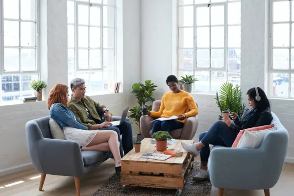 Creative, discussion and business people in the office lounge or coworking space planning project in collaboration. Teamwork, diversity and team working together with technology on sofa in workplace