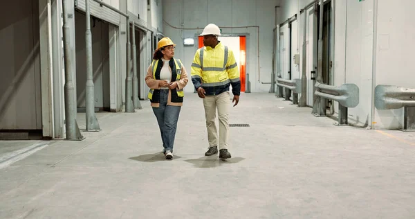 Engineer woman, man and walking in warehouse for planning discussion for manufacturing, logistics or industry. Teamwork, thinking and brainstorming for vision, supply chain and commerce in factory.