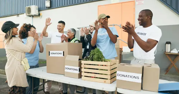 Volunteer, celebration and people with box for donation, charity drive and community service. Collaboration, volunteering and excited men and women clapping for success in NGO, recycle and teamwork.