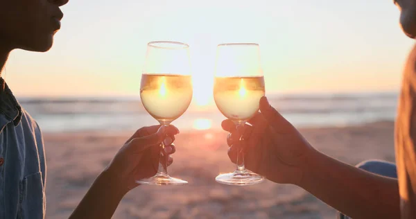 Sunset, beach and couple with wine, toast and anniversary with happiness, marriage and vacation. Romance, man and woman with alcohol, cheers or relationship with seaside holiday, lens flare or luxury.