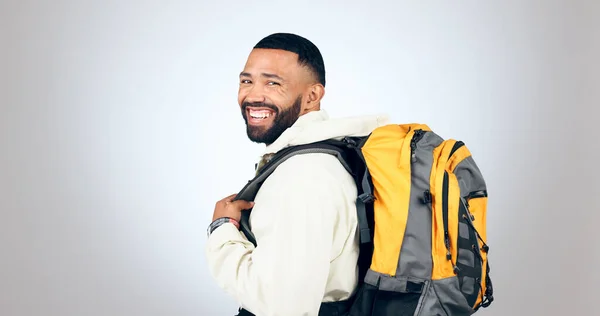 stock image Man, happy portrait and hiking in studio with backpack and smile from travel and freedom with adventure. Camping, fitness and grey background and walking with trekking gear for vacation and holiday.