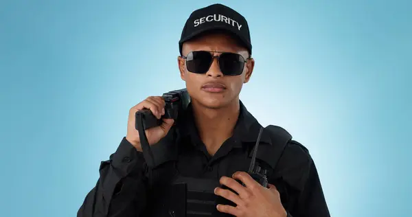 Portrait, security guard and serious man in sunglasses, safety protection service or law enforcement. Face, cop and police officer for justice, danger or crime in studio isolated on a blue background.