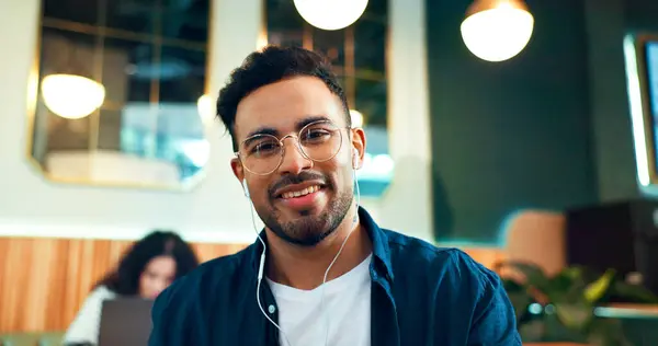Man, portrait and smile with glasses in restaurant for relax, remote work or networking with earphones in the morning. Person, face and listening to music for peace, coffee break or happiness in cafe.