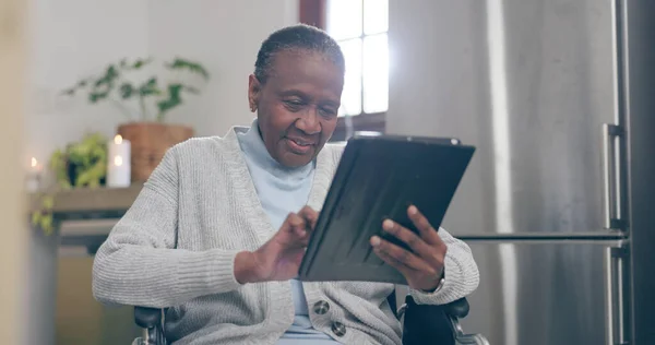 Old woman, wheelchair and tablet happy for online connection, internet reading or social media search. Black person, mobility assistance and digital typing or distance communication, email in kitchen.