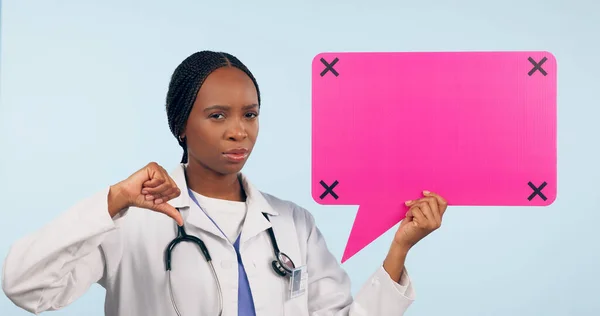 Black woman, doctor and thumbs down with speech bubble for social media or bad review against a studio background. Portrait of African female person, surgeon or nurse showing icon, no sign or mockup.