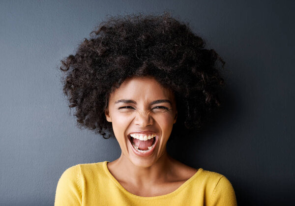 Laughing, black woman and funny portrait in studio with happiness, freedom or wellness in mockup space. Happy, face and African person with smile, emoji and crazy reaction on grey background.