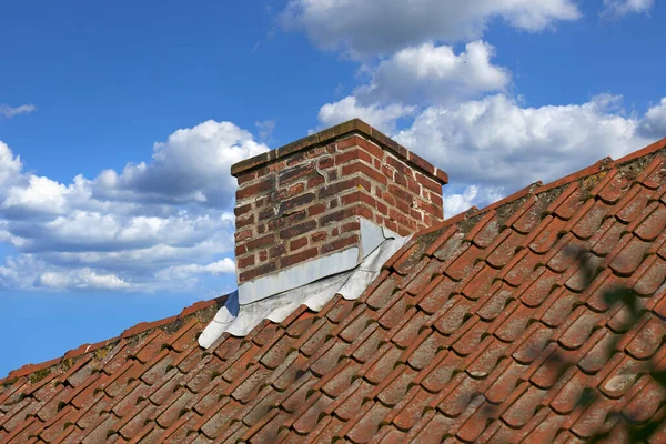 红砖烟囱 设计在屋外的石板屋顶上 与蓝天相对照 背景为白云 在天台建造外逃生槽 供作壁炉烟道及热气之用 — 图库照片