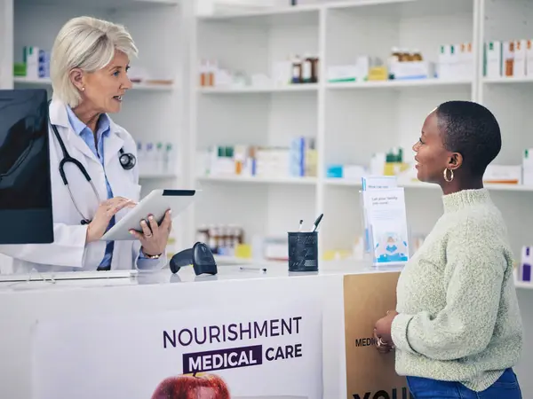 Woman, pharmacist and tablet for consulting patient, prescription or healthcare advice at pharmacy. Female person or medical professional with technology talking to customer in consultation at clinic.
