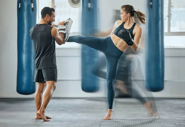 Fighting female training with coach, learning kickboxing exercise at gym and doing cardio fitness workout for wellness with trainer at health club. Woman and man staying, active, healthy and sporty.