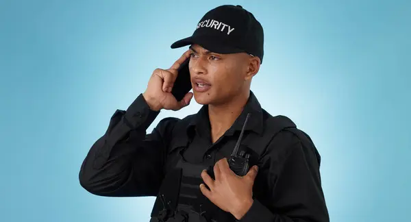 Security guard, phone call and man with communication in a studio with police and law enforcement. Blue background, surveillance and officer with mobile discussion and talking for safety and danger.