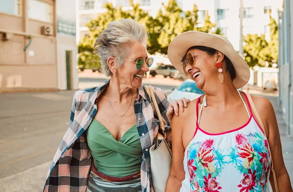 Happy, senior women and laugh in city for walking, travel and bonding on vacation and city street background. Smile, conversation and old people friends relax on walk, laughing and retirement holiday.