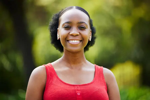 Portrait, happy and black woman in park, outdoor and garden with natural confidence, good mood and freedom in Nigeria. Face, african female person and smile for summer holiday or relax in nature.