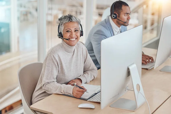 Computer, portrait and an elderly woman in a call center for customer service, support or assistance online. Contact, smile and happy senior consultant working at a desk in a professional crm office.