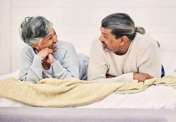 Happy, talking or old couple in bedroom to relax, enjoy conversation or morning together at home. Speaking, senior woman or funny elderly man laughing or bonding with love or smile in retirement.