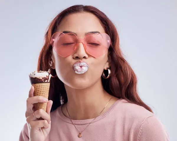 Kiss, ice cream and face of woman with sunglasses in studio with dessert, snack and sweet treats. Kissing emoji, fashion and female person with gelato cone in trendy accessories, style and cosmetics.