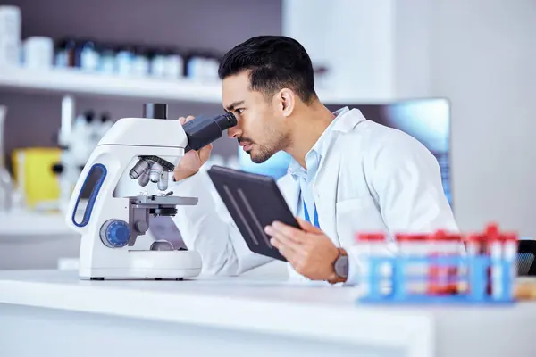 Science, microscope and man on tablet in laboratory for research, test and sample analysis. Digital tech, biotechnology and scientist with medical equipment for vaccine study, analytics and medicine.