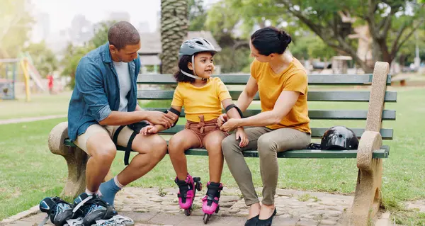 Family, rollerskate and interracial parents help kid with safety pads teaching her skating at the park and bonding outdoors. Mother, father and daughter learning to skate from mom and dad.
