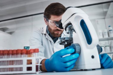 Laboratuvarda çalışan, test tüpünde kimyasal DNA inceleyen ve Almanya 'da bilimsel biyoteknoloji araştırması yapan bir adam. Patoloji bilimcisi, sıvı çözelti ve mikroskop tıp bilimindeki kariyere odaklanıyor.