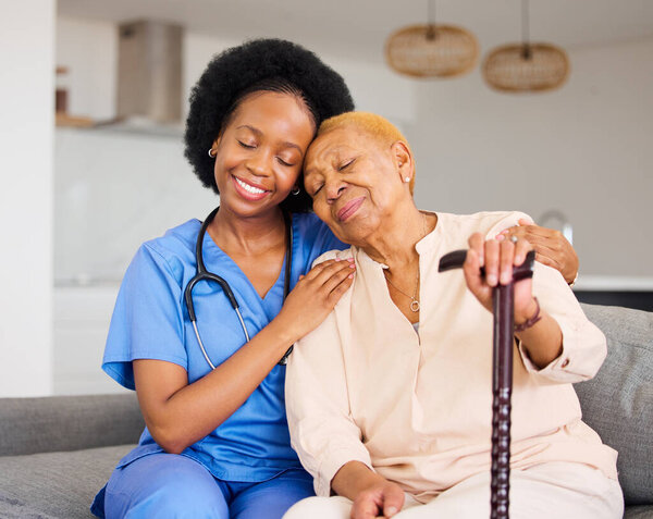 Black woman, nurse and senior patient in elderly care, hug and healthcare on living room sofa at home. Happy African medical professional or caregiver help person with kindness and cane in house.
