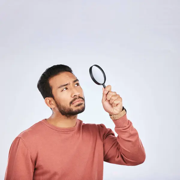 Magnifying glass, man and serious in a studio with investigation for clues. Isolated, white background and male person with inspection for scam, crime evidence and information search with mockup.