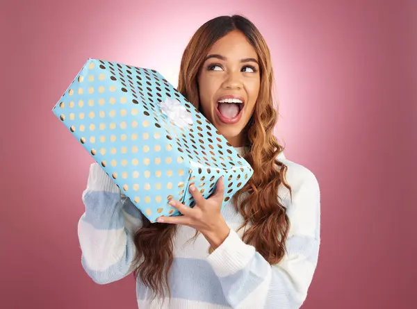 Woman, gift box and studio with thinking, happiness and surprise celebration by gradient background. Student girl, young and happy with present package, excited face and celebrate birthday with smile.