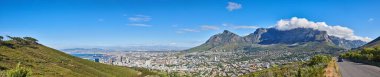 Güneşli bir günde Cape Town ve dağ manzarası geniş açılı. Mavi bir ufukta güzel bir şehir manzarası. Güney Afrika 'daki Table Dağı' nda turistler ve yürüyüşçüler için popüler bir tatil beldesi.