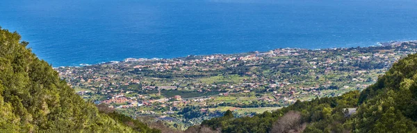 stock image Landscape of a coastal city between hills and mountains from above. A peaceful village beside calm blue ocean water in the Canary Islands. High angle view of Los Llanos, La Palma in summer.