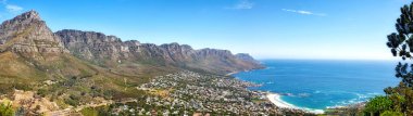 Popüler bir turizm merkezindeki kentsel bir şehri çevreleyen dağları olan güzel bir kıyı manzarası. Dağ çıkıntıları olan Cape Town şehrinin havadan görünüşü ve mavi gökyüzünde fotokopi alanı olan okyanus..