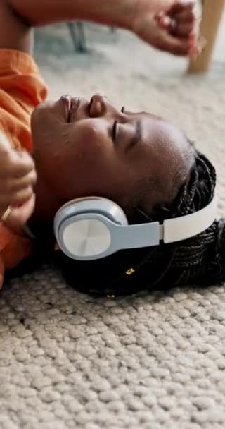 耳机和快乐的黑人女人在家里客厅的地板上 听着音频或声音放松 在地毯流媒体上发笑 听音乐 享受科技的自由 — 图库视频影像