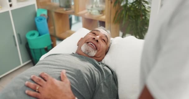 生理療法 シニアマン コンサルティングセラピストは または背中の痛みの回復のためにベッドから アセスメントオフィスの理学療法 理学療法士 高齢男性患者 — ストック動画